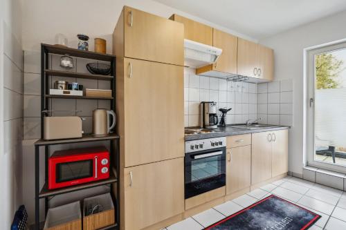 cocina con armarios de madera y microondas rojo en Comfort Apartment - bis 4 Pers - Neunkirchen City - Parkplatz - Garage - WiFi - Bad - Balkon en Neunkirchen