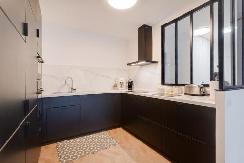 - une cuisine avec des placards noirs et un évier dans l'établissement Élégance - DisneyLand Paris - Vallée Village - 7 à 9 personnes, à Serris