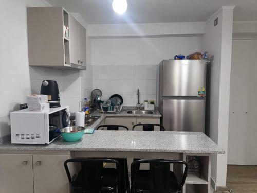 a kitchen with a refrigerator and a counter with chairs at Relájate en Valparaíso y Viña del Mar in Viña del Mar