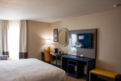 a hotel room with a bed and a desk and a mirror at Comfort Inn & Suites Geneva- West Chicago in Geneva