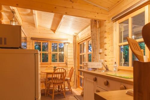 a log cabin kitchen with a table and chairs at Family friendly sunny Log Cabin in Wimborne Minster