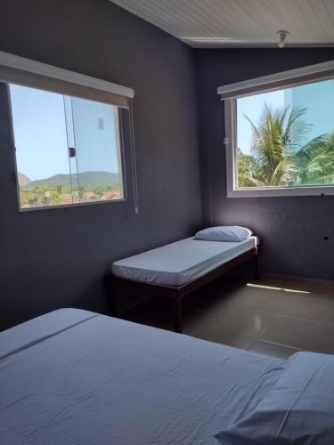 a small room with two beds and two windows at Espaço Verano- quarto Família in Niterói