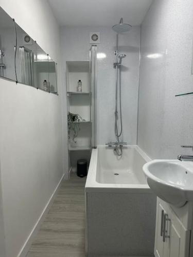a white bathroom with a tub and a sink at Combie Lane Apartments in Oban