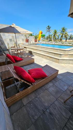 Duas espreguiçadeiras e um guarda-sol ao lado de uma piscina em Jatobá Praia Hotel em Aracaju