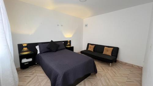 a bedroom with a black bed and a couch at Acogedor apartamento esquinero, a una cuadra del parque principal in Líbano