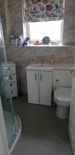 a bathroom with a toilet and a sink and a window at Lawford Close in Madeley