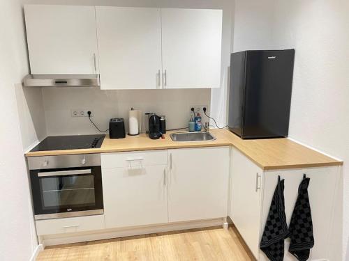 a kitchen with white cabinets and a black appliance at Moderne Wohnung in Unna Mitte in Unna