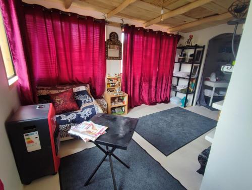 a room with red curtains and a couch and a table at Hôte sahara & spa TADIGHOUST in El Hara