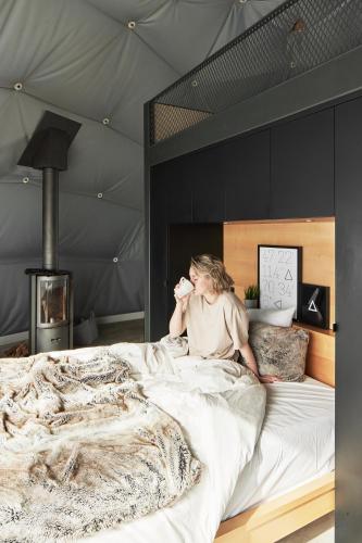 a woman sitting on a bed in a tent at Dômes Charlevoix in Petite-Rivière-Saint-François
