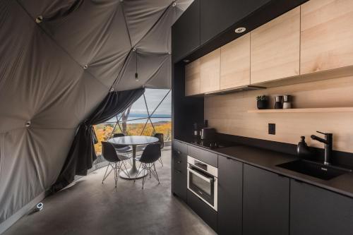 - une cuisine avec une table et une vue sur l'océan dans l'établissement Dômes Charlevoix, à Petite-Rivière-Saint-François