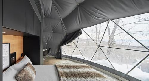 a bedroom with a bed and a large window at Dômes Charlevoix in Petite-Rivière-Saint-François