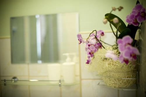 a vase with purple flowers on a shelf in a bathroom at Noclegi na Wzgórzu Zamkowym in Przemyśl