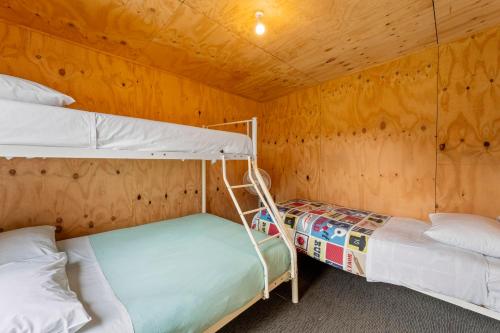 two bunk beds in a room with a wooden wall at Bach Haven - Mangakino Holiday Home in Mangakino