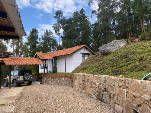 a white house with a stone wall next to a hill at REFUGIO LA CASONA in Cucaita