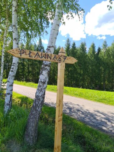 a wooden sign in the grass next to a road at Willa Spokojne Wzgórze in Pławna