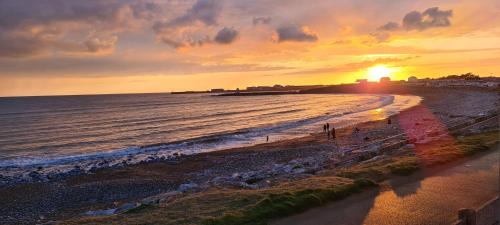 a sunset on a beach with the ocean at Thistle 83 in Porthcawl