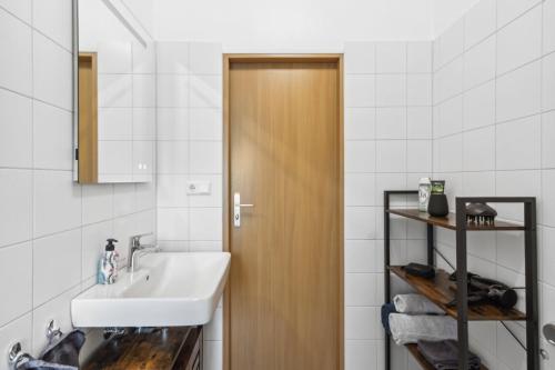 La salle de bains est pourvue d'un lavabo et d'une porte en bois. dans l'établissement Zigarrenhof Apartment in Citynähe inkl. Netflix, à Aschaffenbourg
