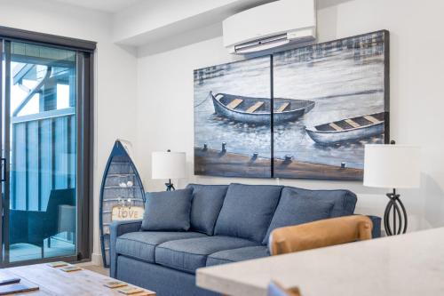 a living room with a blue couch and a painting of boats at Seas The Day Saratoga at THE BEACH HOUSE in Campbell River