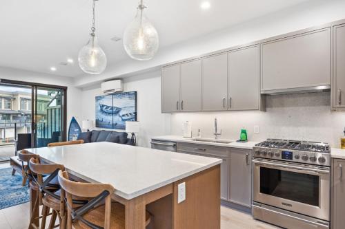 a kitchen with white cabinets and a table with chairs at Seas The Day Saratoga at THE BEACH HOUSE in Campbell River