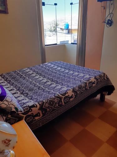 a bed sitting in a room with a window at Hostal Vista al Lago Titicaca Puno in Puno