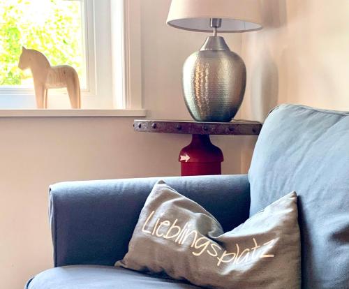 a pillow on a blue couch next to a lamp at Ahrentschildt's Ferienwohnung im Reetdachhaus in Eyendorf