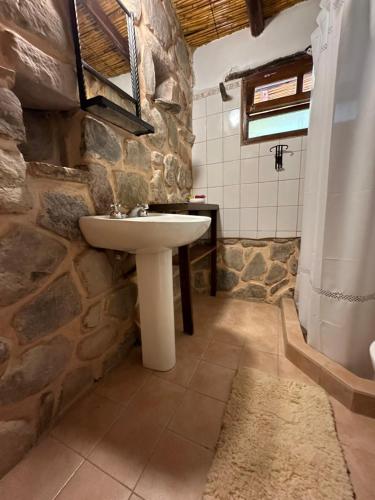a bathroom with a stone wall and a sink at La Hoyada in Tilcara