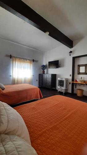 um quarto de hotel com duas camas com lençóis laranja em Casa Gardenia Hotel em Tecozautla
