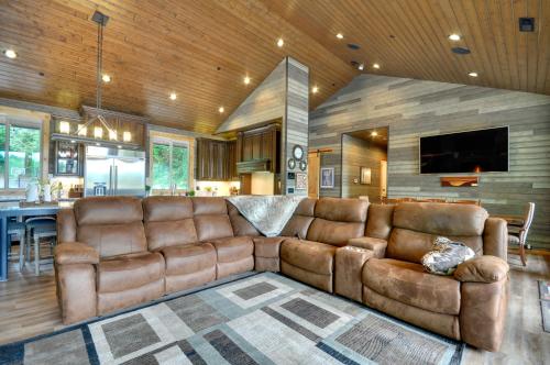 a living room with a brown leather couch and a tv at Luxurious Waterfront Retreat with Private Pond! in Ridgefield