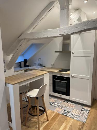 une cuisine avec des placards blancs et une table avec un tabouret dans l'établissement Appartement Lou, hyper centre, au cœur de Troyes, à Troyes