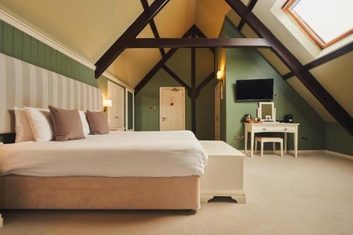 een slaapkamer met een groot bed en een bureau bij Rose and Crown Yealmpton in Yealmpton