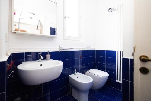een blauw betegelde badkamer met een wastafel en een toilet bij Casa Al Duomo in Parma