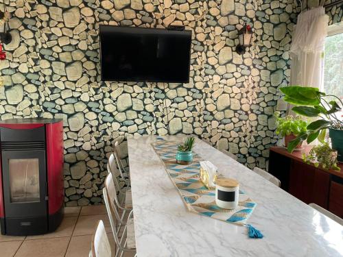 comedor con mesa y TV en una pared de piedra en Hospedaje La Blanquita, en Santa Juana
