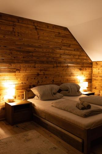 a bedroom with a bed with a wooden wall at Chata pod Starou Horou in Trstená