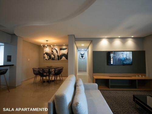 a living room with a couch and a tv on a wall at ApartDamani - Aptos por Temporada no centro in Foz do Iguaçu