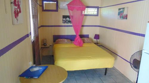 una piccola stanza con un letto giallo e un tavolo di Caribgites a Sainte-Anne