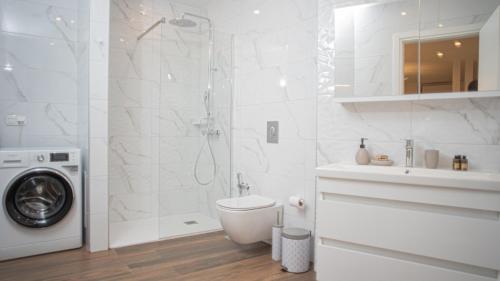 a white bathroom with a shower and a washing machine at Mystique Boutique Residence in Kalabaka