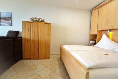 een slaapkamer met een bed en een houten kast bij Strandhochhaus SG10 in Cuxhaven