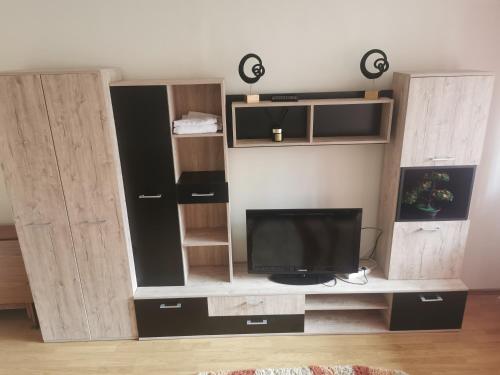 sala de estar con TV y algunos armarios de madera. en Milan's Apartment, en Miercurea-Ciuc