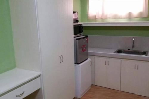 una pequeña cocina con armarios blancos y fregadero en Jocanai Residences Studio C, en Lusong
