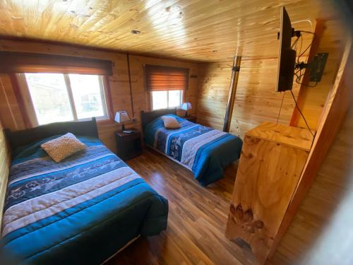 a bedroom with two beds in a wooden cabin at Hospedaje Alto Palena de Puerto Cisnes in Puerto Cisnes