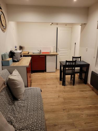 a living room with a table and a kitchen at Petite maisonnette in Pont-Sainte-Maxence