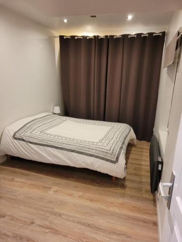 - une chambre avec un lit et un rideau gris dans l'établissement Petite maisonnette, à Pont-Sainte-Maxence