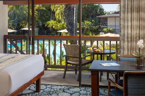 a bedroom with a bed and a balcony with a table at Catamaran Resort Hotel and Spa in San Diego