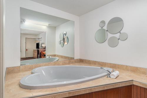 Howard Johnson by Wyndham Traverse City في ترافيرس سيتي: حوض كبير في الحمام مع مرآة