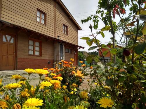 a garden with yellow flowers in front of a house at Cabañas Don Carlos in El Hoyo