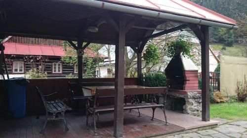 a wooden pavilion with a bench and a grill at Chalupa U Potoka in Staré Hory