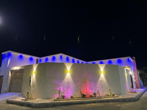 ein weißes Gebäude mit blauen Lichtern in der Nacht in der Unterkunft لاڤانا in Unaizah