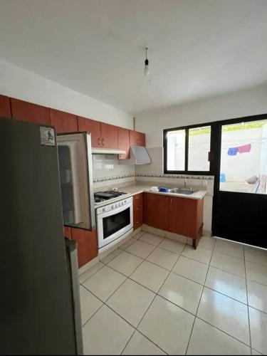 a kitchen with brown cabinets and a white tile floor at Chakalito in Tonalá