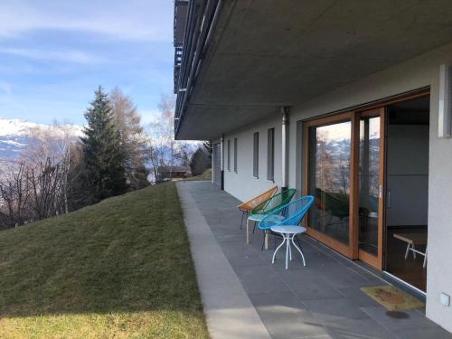 a patio with two chairs and a table on the side of a building at Joli appartement 2 pièces et demi tout confort, Balcon du Ciel NAX Mont-Noble in Nax