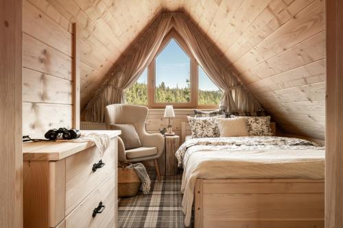 une chambre avec un lit et une chaise dans un grenier dans l'établissement Luxury chalet WRÓBLOWA CHAŁUPKA przy Dolinie Chochołowskiej, à Kościelisko